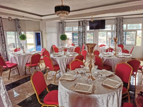 une chambre avec des tables et des chaises rouges et une chambre avec des tables et des chaises longues dans l'établissement TCHATCHA HOTEL, à Yaoundé