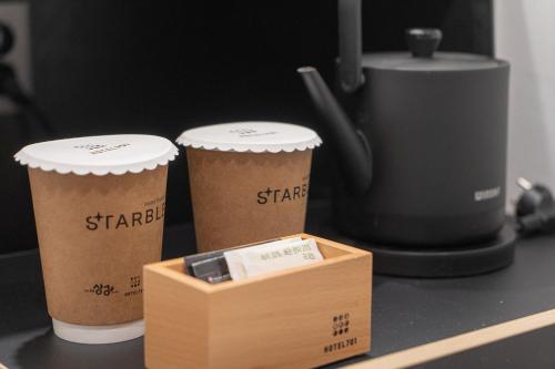 two cups of coffee on a counter with a box at Hotel 701 Gyeongju in Gyeongju