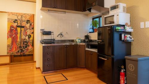 a kitchen with a black refrigerator and a microwave at Geisha House Atami - fireworks view in Atami