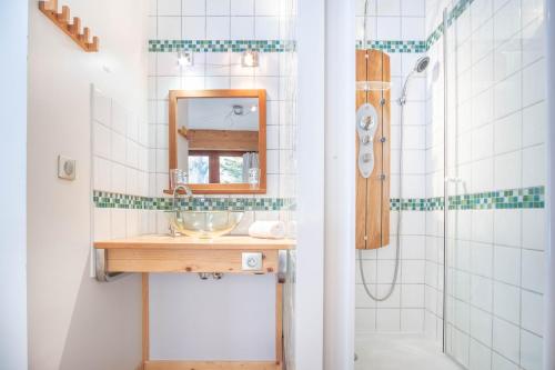 La salle de bains est pourvue d'un lavabo, d'un miroir et d'une douche. dans l'établissement Les Tussilages - Terrasse vue Mont-Blanc, à Chamonix-Mont-Blanc