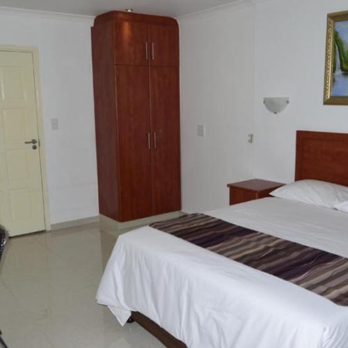 a bedroom with two beds and a wooden cabinet at Royal Ushaka in Durban