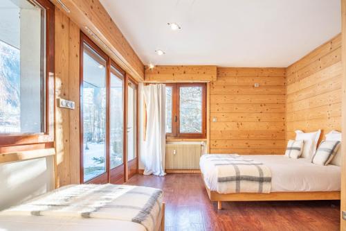 - 2 lits dans une chambre dotée de murs en bois et de fenêtres dans l'établissement Les Tussilages - Terrasse vue Mont-Blanc, à Chamonix-Mont-Blanc