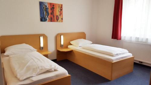 2 Betten in einem kleinen Zimmer mit 2 Lampen in der Unterkunft G&K Hotel in Guntramsdorf