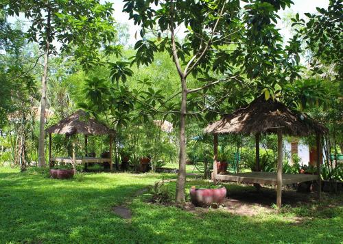 a park with two huts and a bench in the grass at Sabbay Kep in Kep