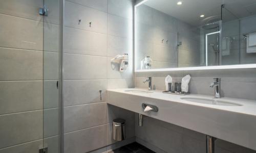 Baño con 2 lavabos y espejo en Thon Hotel Snø en Lorenskog