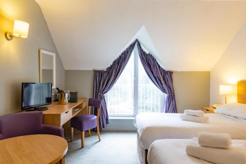 サンダウンにあるThe Broadway Park Hotelのベッド2台、デスク、窓が備わるホテルルームです。