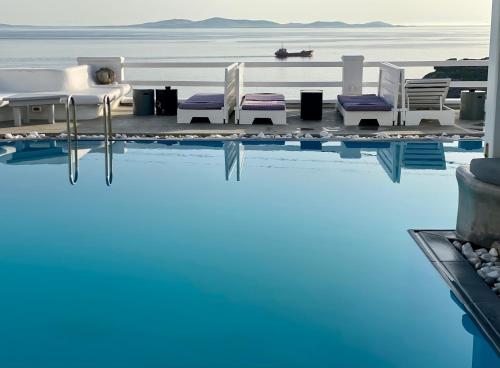 a pool with chairs and a bed and the water at Flaskos Suites and more in Agios Stefanos