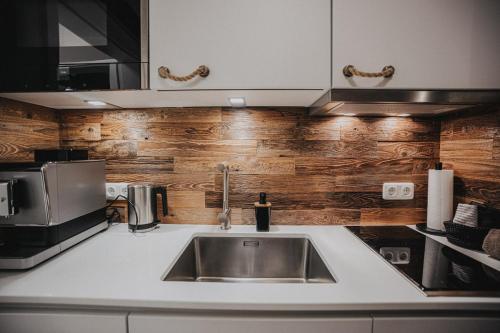 a kitchen with a sink and wooden wall at Friesenhus Dangast in Dangast