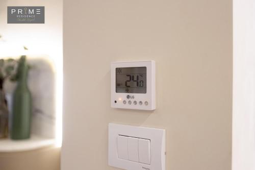 a white clock on a wall with a switch at Prime Residence Sheikh Zayed in Sheikh Zayed
