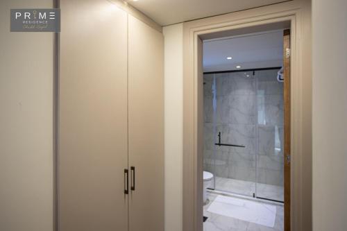 a bathroom with a toilet and a glass shower door at Prime Residence Sheikh Zayed in Sheikh Zayed