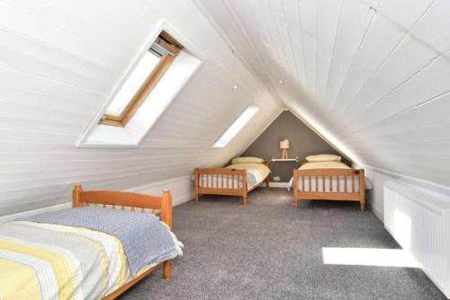 a attic bedroom with two beds and two windows at Impeccable 2-Bed Cottage in Johnshaven in Montrose