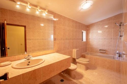 een badkamer met een wastafel, een toilet en een spiegel bij A House With a View in Aljezur
