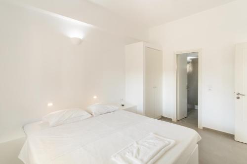 a white bedroom with a bed with white sheets and pillows at Andriana's cycladic house close to the sea in Drios