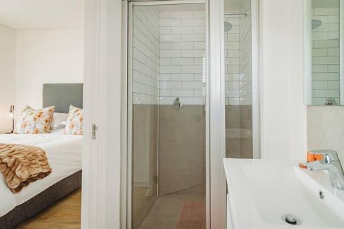 a bathroom with a glass shower and a bed at 304 Le Jardin in George
