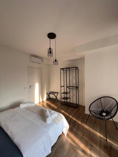 Appartamento Business Milano في ميلانو: غرفة نوم بيضاء بسرير وكرسي