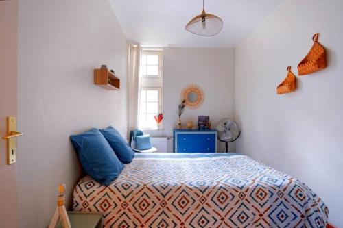 Un dormitorio con una cama con almohadas azules y una ventana en Au charme d'antan - Un joyau caché en Troyes