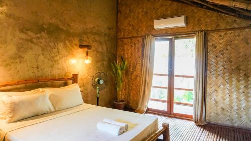 a bedroom with a bed and a large window at Happiness Vacation Villa El Nido in El Nido