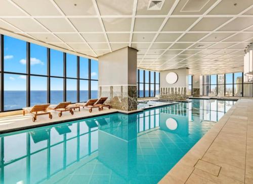 a swimming pool with chairs and a view of the ocean at Surfers Paradise New Beachfront Apartments in Gold Coast