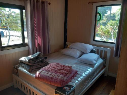 - un petit lit dans une chambre avec 2 fenêtres dans l'établissement maison thailande pran buri, à Pran Buri