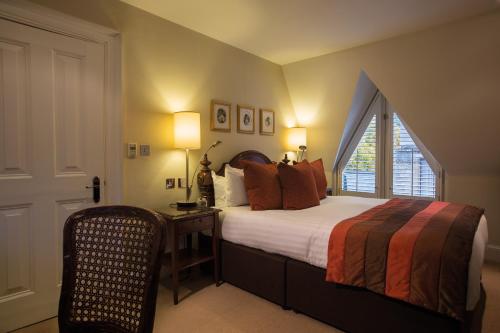 1 dormitorio con cama, ventana y silla en Ettington Park Hotel, Stratford-upon-Avon, en Stratford-upon-Avon