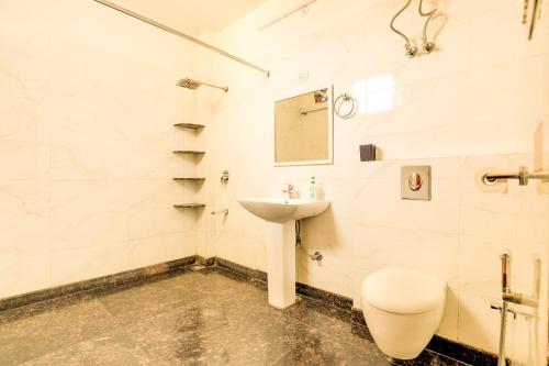 Baño blanco con lavabo y aseo en House Of Comfort Greater Noida Luxury, en Greater Noida