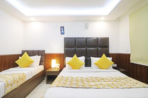 two beds in a hotel room with yellow pillows at Hotel Mayda Prime Near Delhi Airport in New Delhi