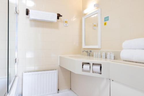 a white bathroom with a sink and a mirror at The Carlton Hotel in Great Yarmouth