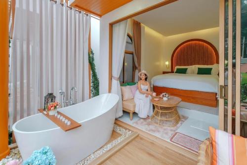 - une femme dans une suite avec un lit et une baignoire dans l'établissement Pangthara65 ปางธารา ณ ปางไฮ เชียงใหม่, à Doi Saket