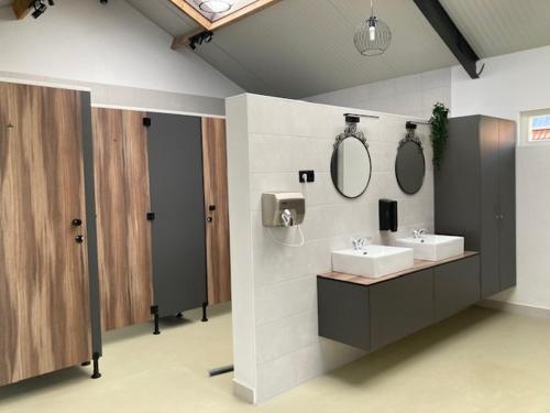 a bathroom with two sinks and two mirrors on the wall at Chalet op mini-camping de Peelweide in Grashoek
