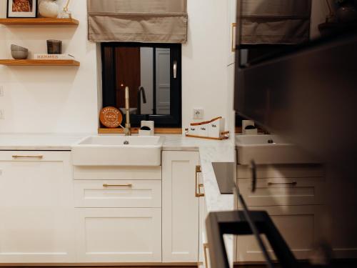 a kitchen with white cabinets and a sink and a mirror at GIA Apartment in Satu Mare