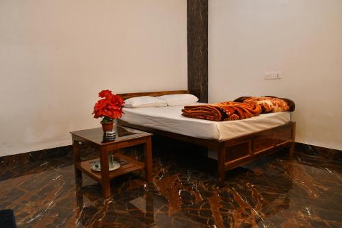 Un dormitorio con una cama y una mesa con un jarrón de flores en Paradise Inn, en Jasidih