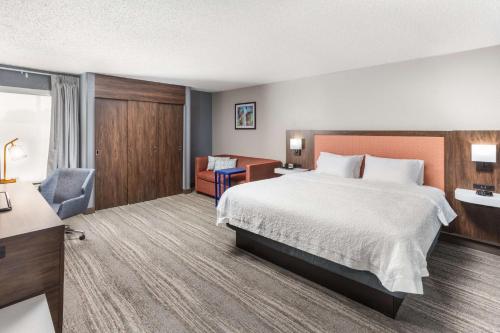 a hotel room with a large bed and a chair at Hampton Inn Joliet/I-55 in Joliet