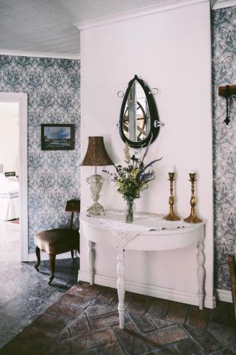 a room with a table with a mirror and a chair at Snällfäll Country living - Åkerbo gård charmigt renoverad flygel in Kristinehamn