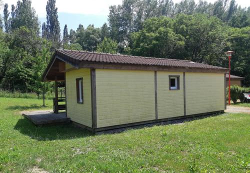 un petit hangar dans un champ d'herbe dans l'établissement Camping Onlycamp Les Peupliers du Lac, à Chindrieux