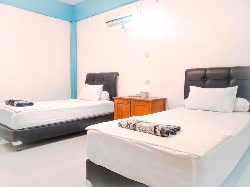 a room with two beds and a wooden table at Raffiel Nias in Lagudri