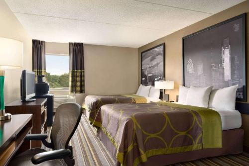 a hotel room with two beds and a television at Super 8 by Wyndham Chambersburg I-81 in Chambersburg