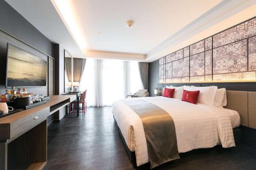 a hotel room with a large bed and a desk at Ramada Plaza by Wyndham Chao Fah Phuket in Phuket Town
