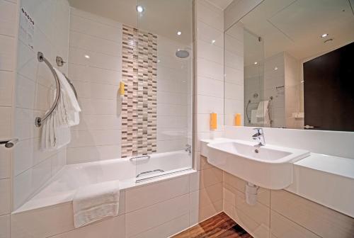 a white bathroom with a tub and a sink at Premier Inn Dubai Al Jaddaf in Dubai