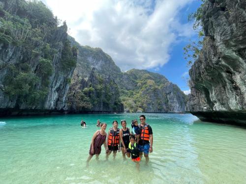 a group of people standing in the water at a beach at Hidden of Cailan Extension Transient House in El Nido