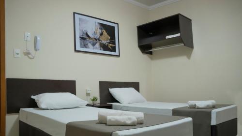 a room with two beds and a flat screen tv at Dom Hotel Maringá in Maringá
