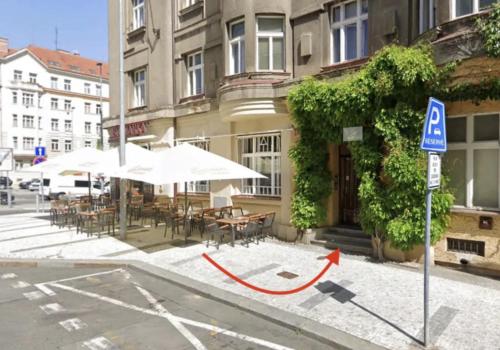 un edificio con mesas y sombrillas en una calle de la ciudad en TOP lokalita u Pražského hradu! en Praga