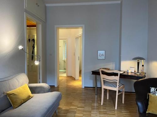 ein Wohnzimmer mit einem Sofa und einem Tisch mit einem Stuhl in der Unterkunft Suite Appartement Friesenhof in Hannover