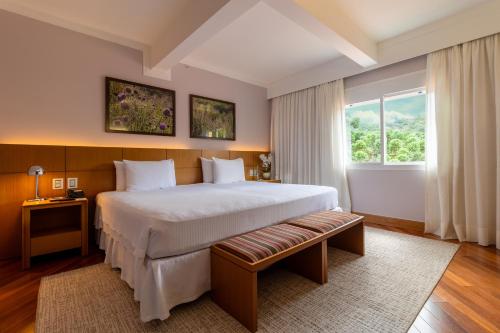 sypialnia z dużym łóżkiem i oknem w obiekcie Grande Hotel Campos do Jordao w mieście Campos do Jordão