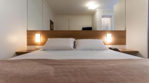 a bedroom with a large bed with two white pillows at Hotel Glória Blumenau in Blumenau