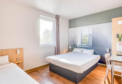 a bedroom with two beds and a window at B&B HOTEL Bordeaux Langon in Langon