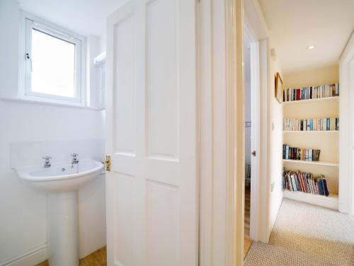 a white bathroom with a sink and a window at Trevarthian in Polzeath