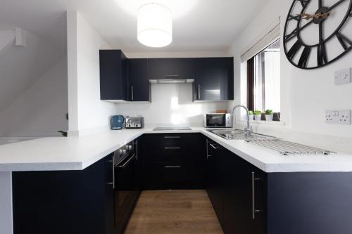 a kitchen with black cabinets and a clock on the wall at Orchard House - 2 bedroom house, Central Alnwick in Alnwick