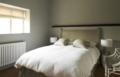 a bedroom with a large white bed and a window at Samphire in Sharrington