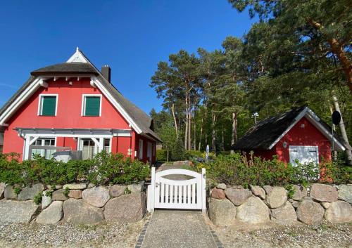 a red house with a white gate and a fence at Strandhaus Usedom in Stubbenfelde