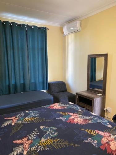 Habitación de hotel con cama y espejo en Unit 11 - Damara Gardens, en Windhoek